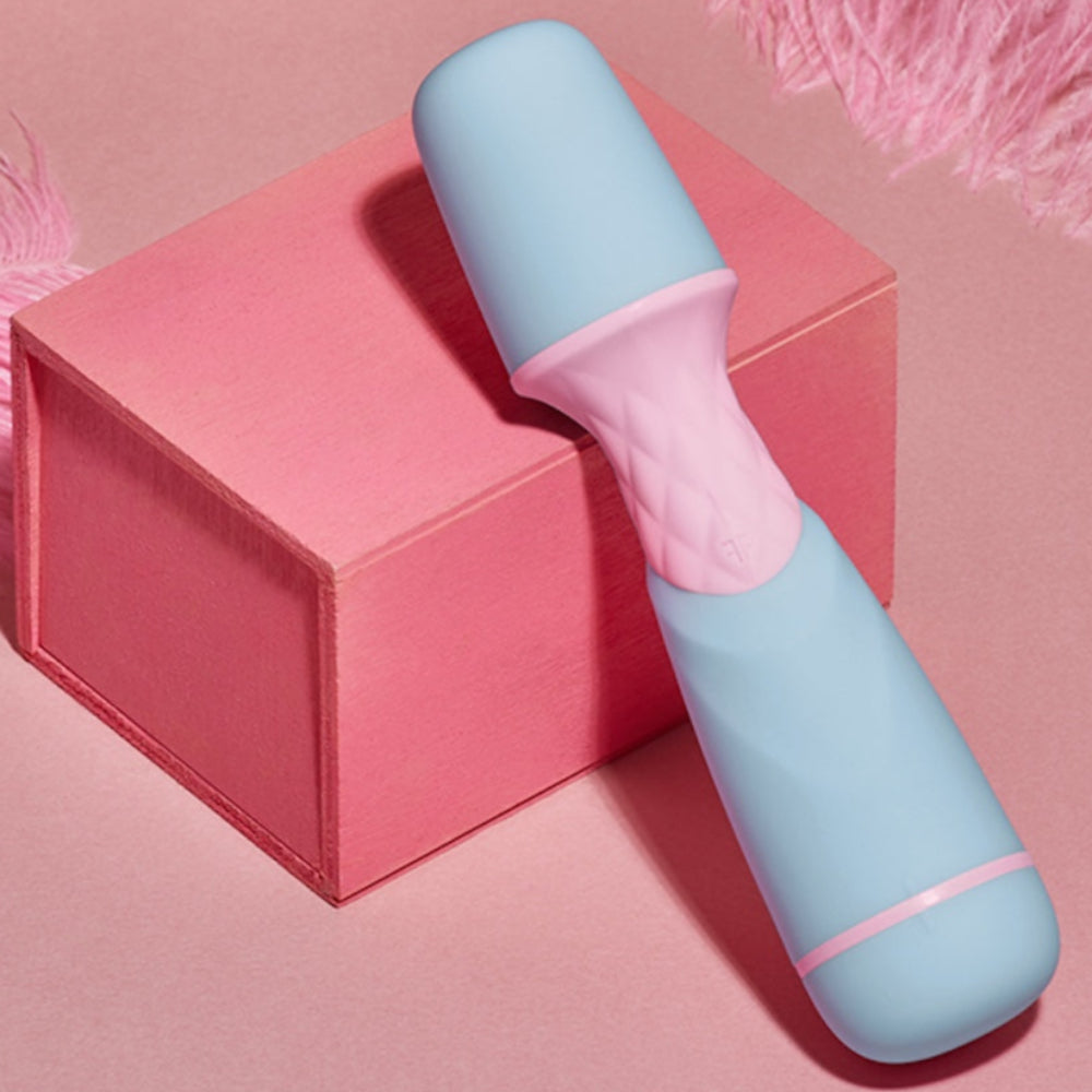 FemmeFun FFIX Mini Battery operated wand vibrator in blue from front propped on a pink silk box in a plush background