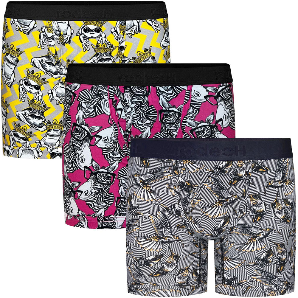 Gender-neutral packer underwear – 3 pairs of Rodeoh Shift Boxers. 1 pair is yellow and gray with frogs wearing crowns. One pair is hot pink with Zebras wearing glasses, and the third pair is a white and black zigzag pattern with hummingbirds. The boxers have a 6-inch inseam, soft waistband, and an optional discreet interior pocket for secure, comfortable packing, designed for nonbinary and trans masc individuals.