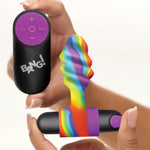Remote control with 'BANG!' branding held by a hand, next to a colorful rainbow-patterned anal plug vibrator.