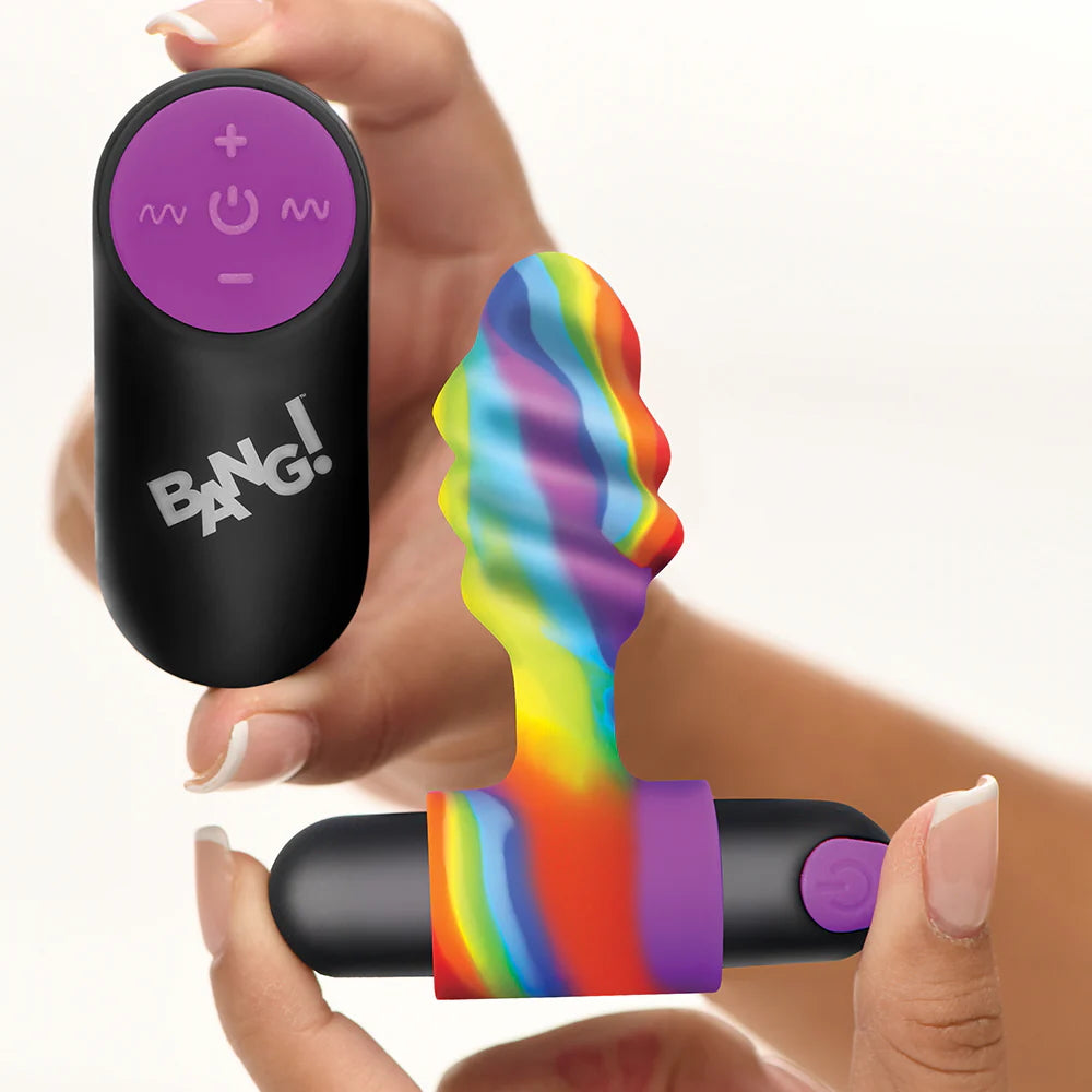 Remote control with 'BANG!' branding held by a hand, next to a colorful rainbow-patterned anal plug vibrator.