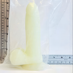 glow in the dark silicone dildo with suction cup base in front of ruler showing dimensions