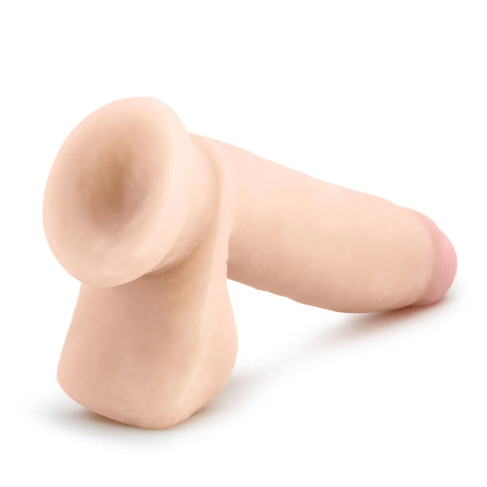 Vanilla Au Naturel Sensafeel dual density dildo with balls and suction base, laying horizontal to the ground with the suction cup exposed 