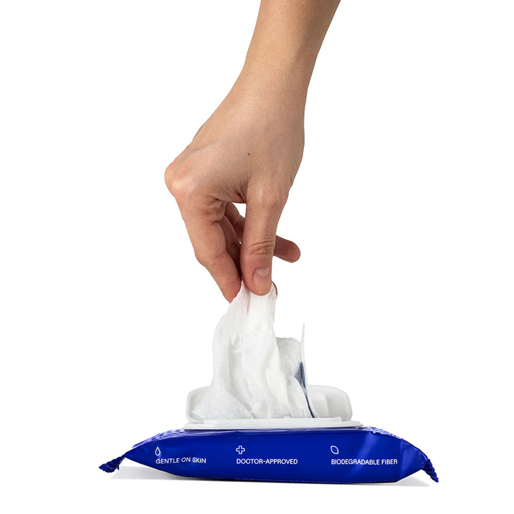Hand reaching for a wipe from a packet of disposable wipes on a white background