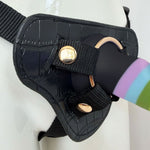 Nexus Fun and Love harness kit with adjustable black strap on harness and Rainbow Prysm tease silicone dildo, with dildo inserted into the harness with the included gold o ring, zoomed in