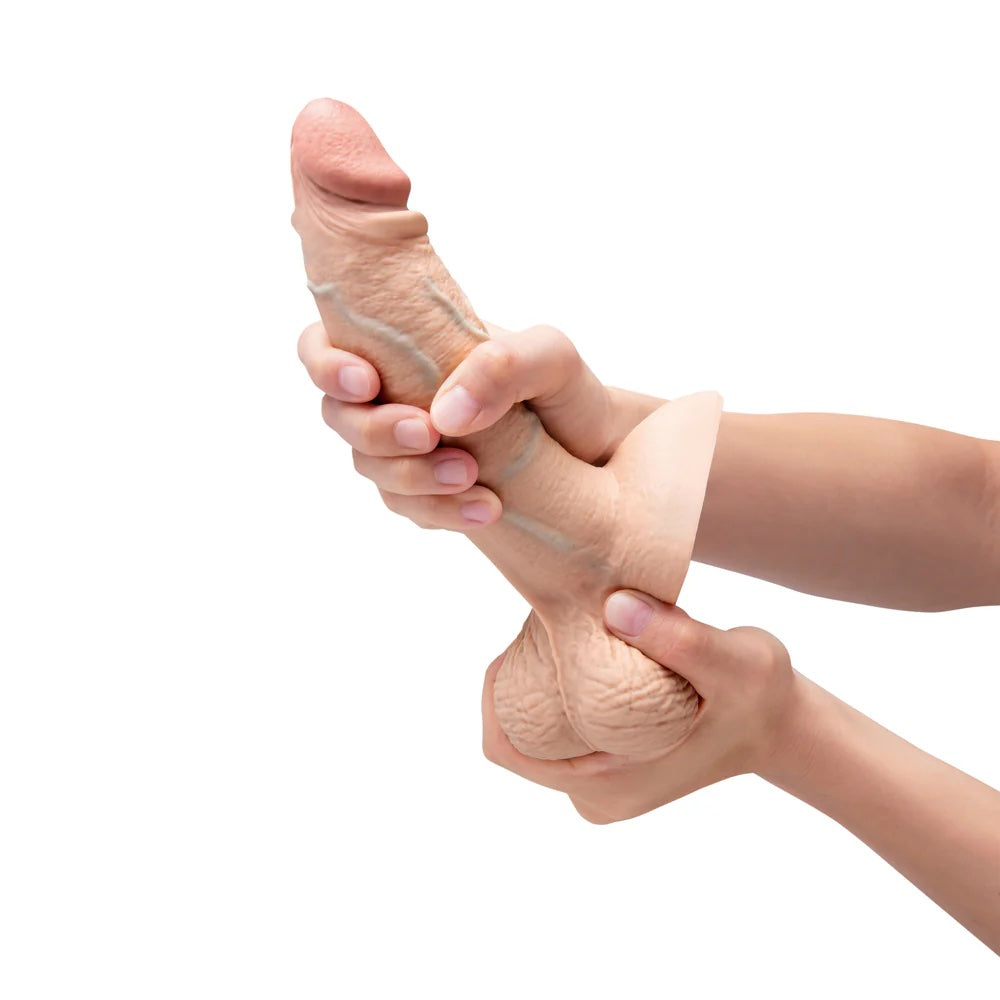 Slipskin Grithy Sliding Skin silicone dildo in Cream, held in hands being bent to show flexiblilty