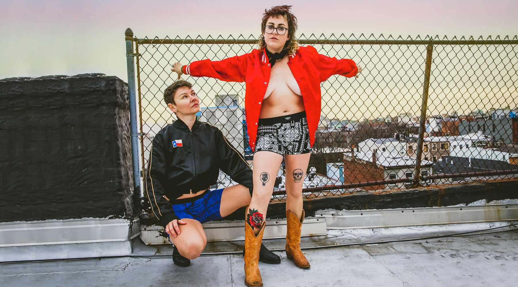 two people one standing against fence the other seated