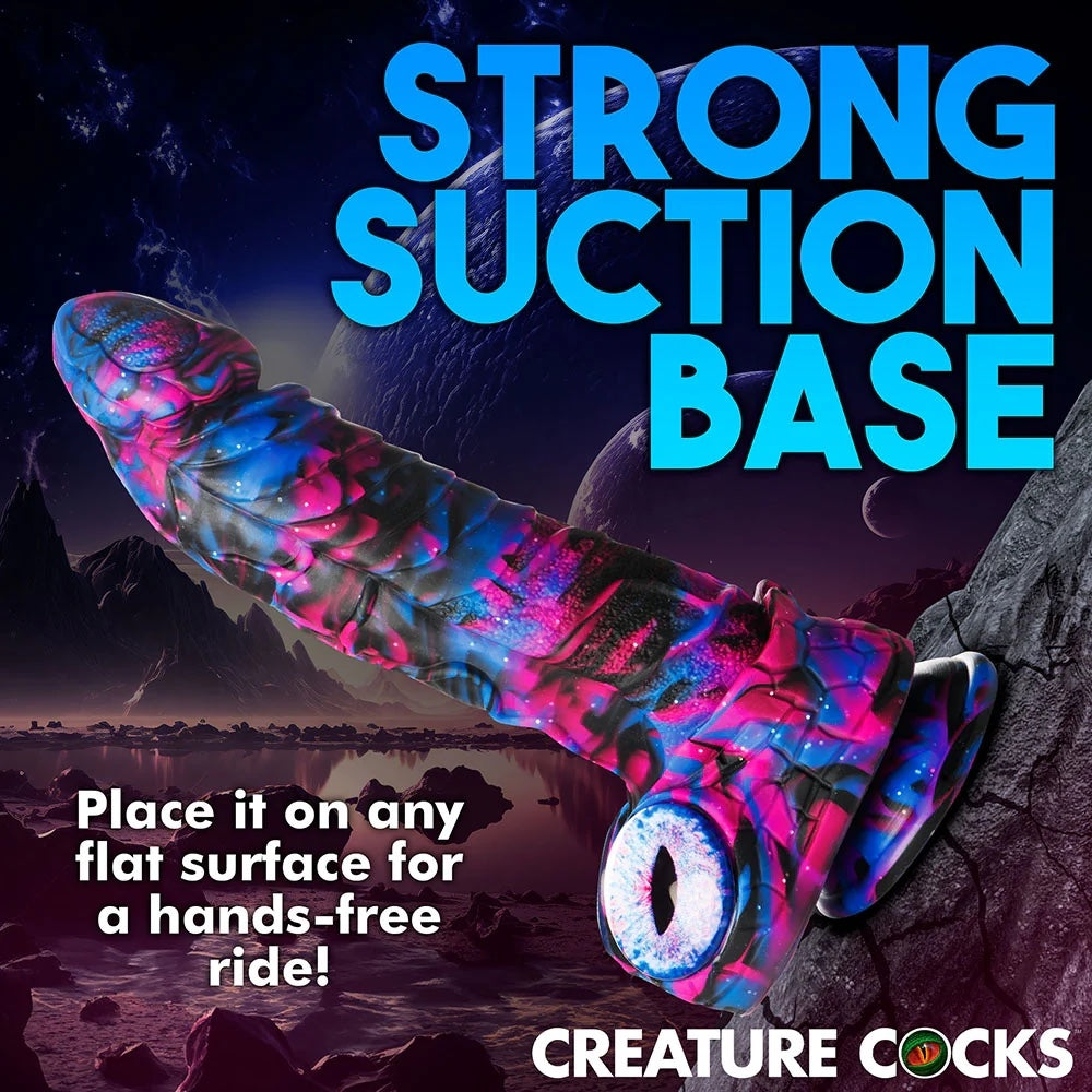 XR Brands Creature Cocks Alienoid Pink, black, blue and glitter silicone fantasy dildo with eye balls for testes side view suctioned to a rock wall