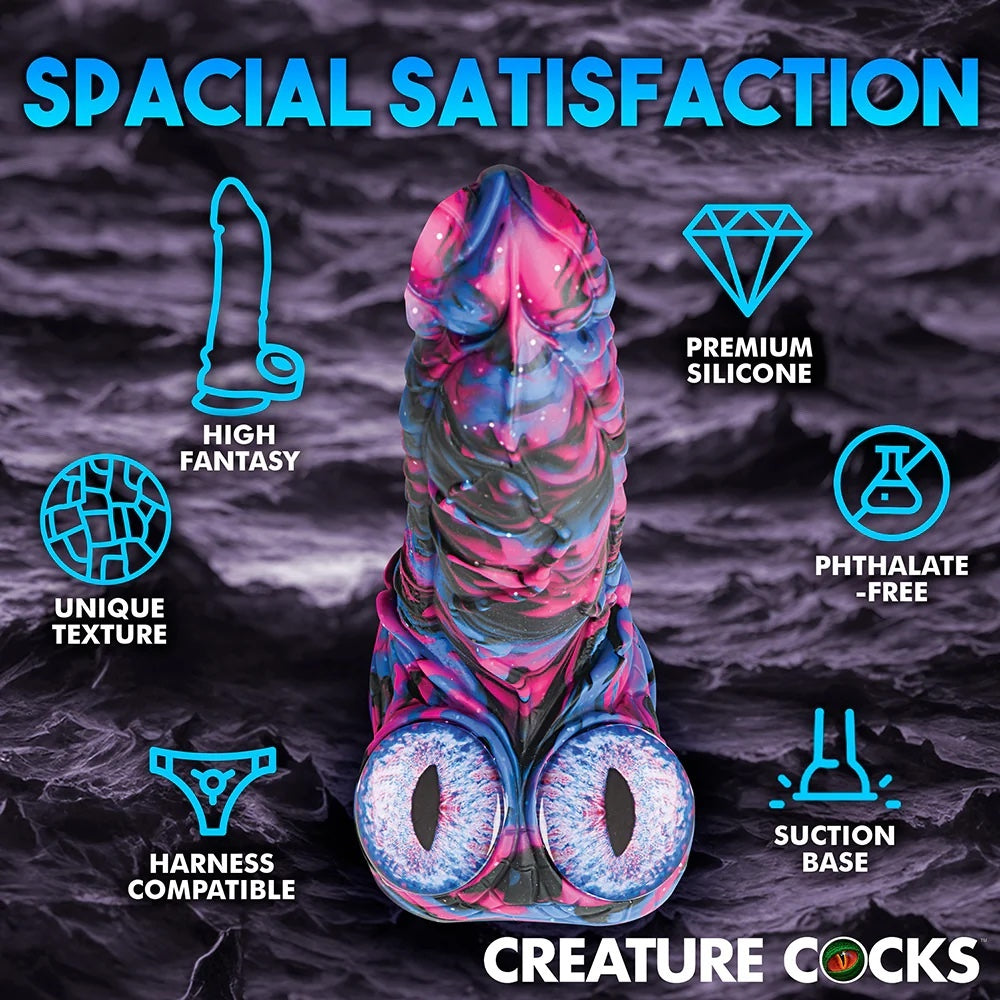 XR Brands Creature Cocks Alienoid Pink, black, blue and glitter silicone fantasy dildo with eye balls for testes from above, with graphic text of the features on a rocky backdrop